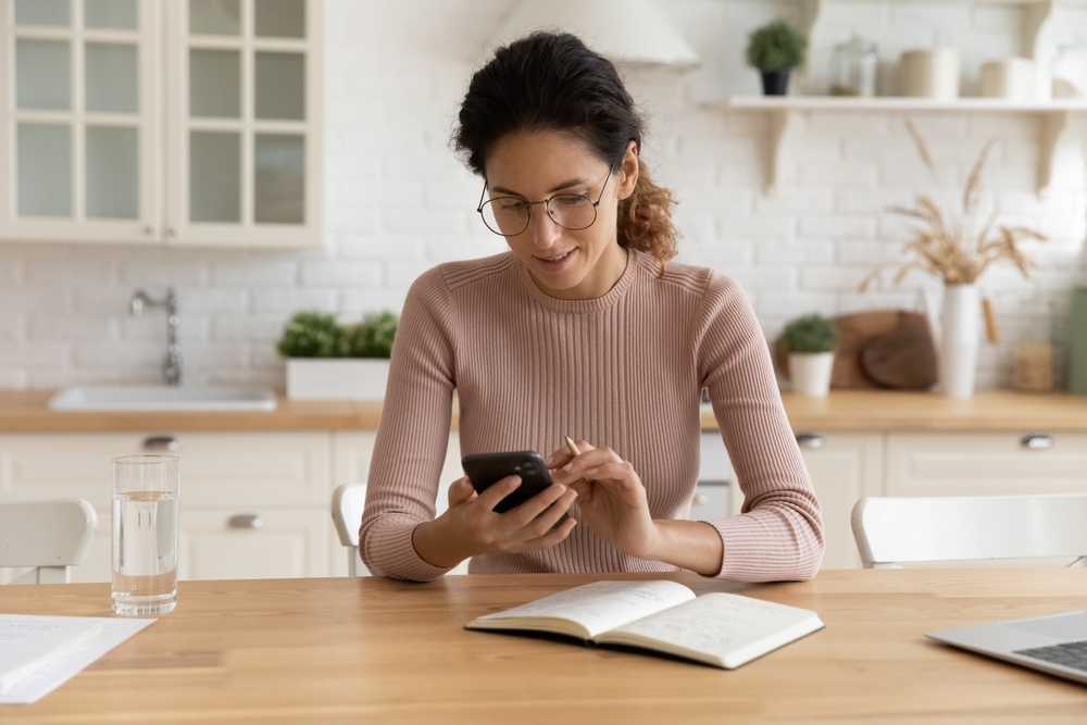 Woman using salon software on her smartphone to book an appointment online, highlighting the convenience of online booking with deposits