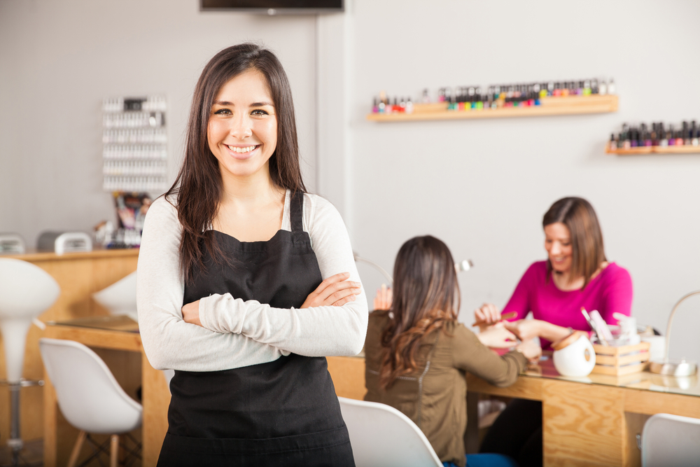 Smiling salon owner standing confidently in front of clients, demonstrating the success of using Simple Salon's software tools