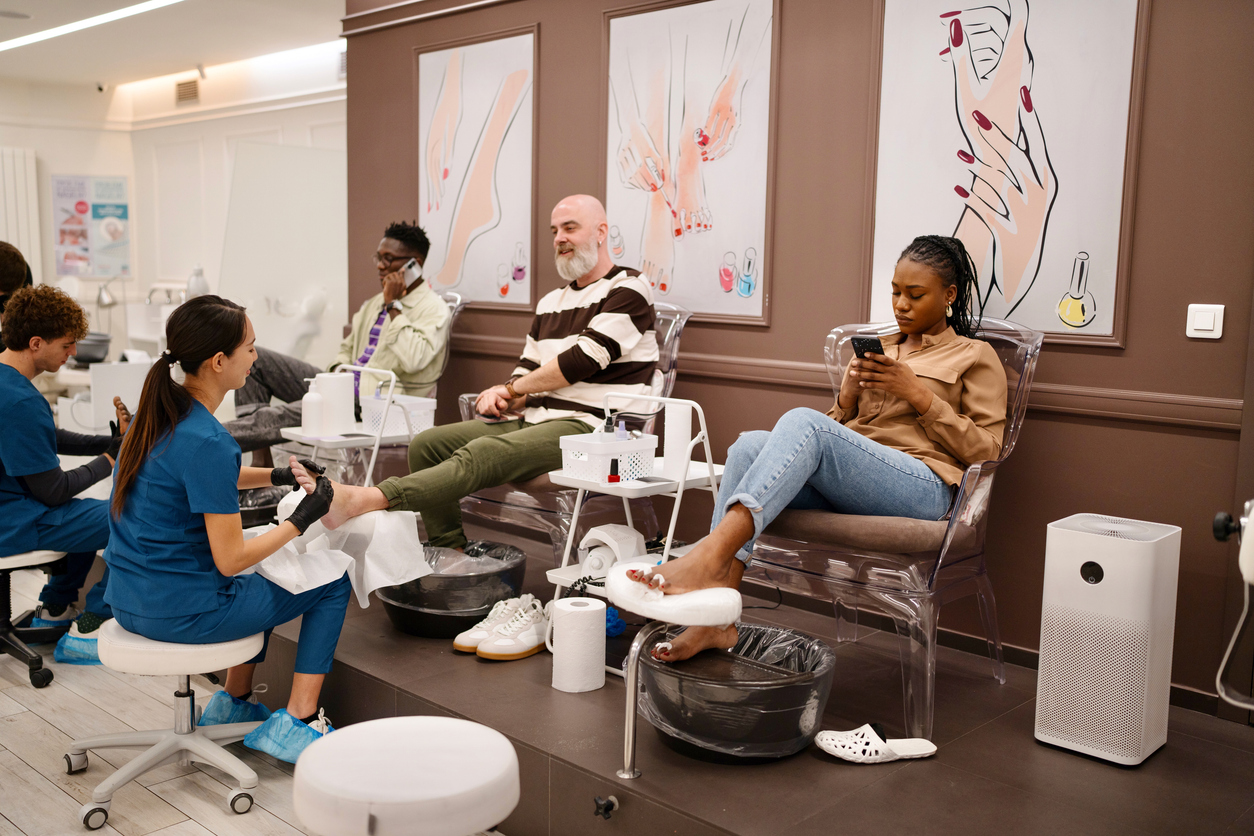 Clients receiving pedicures in a busy nail salon, illustrating the importance of efficient online booking systems to manage high volumes of appointments seamlessly and enhance customer satisfaction.