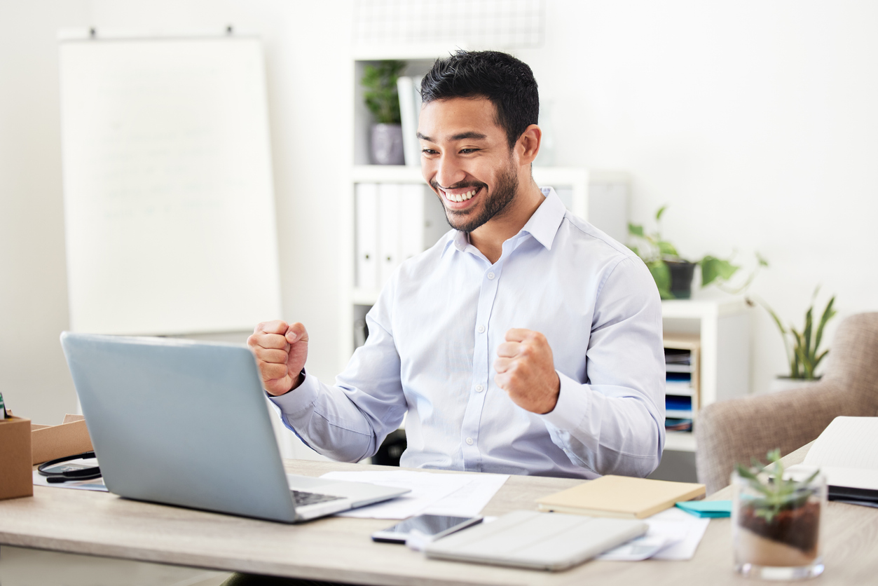 Businessman celebrating success while looking at a laptop, representing the positive impact of using advanced salon software to boost profits and enhance client satisfaction.