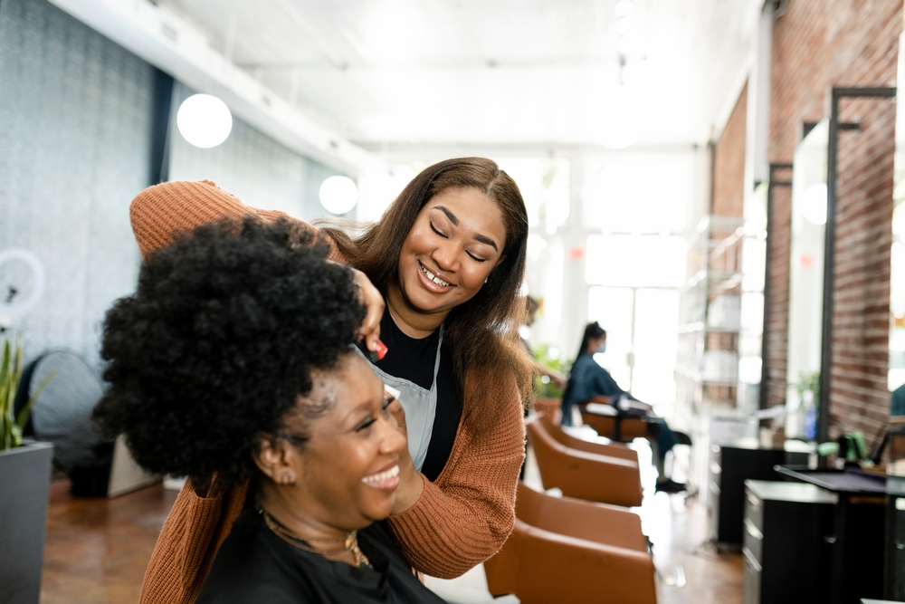 A happy hairstylist and client in a modern salon, illustrating a successful salon program improving customer experience.