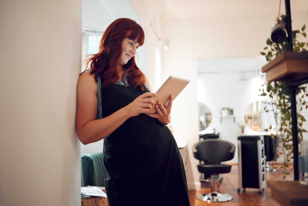 A salon professional using a tablet to manage appointments, showcasing the role of salon software in enhancing customer experience.