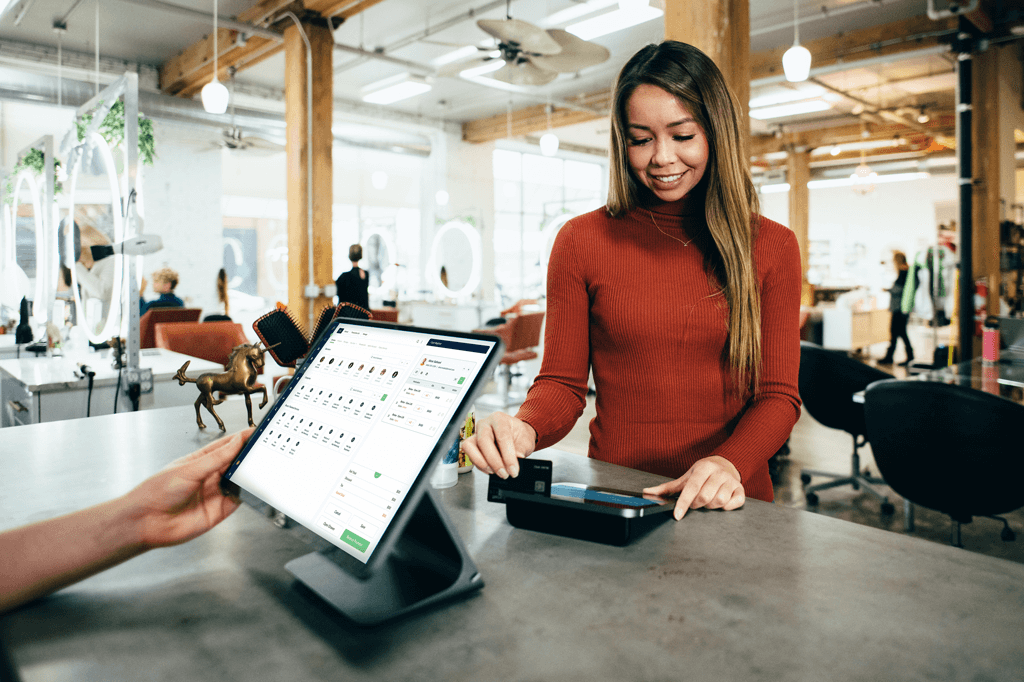 A customer paying at a salon's front desk, highlighting the importance of selecting the right salon software for business success.