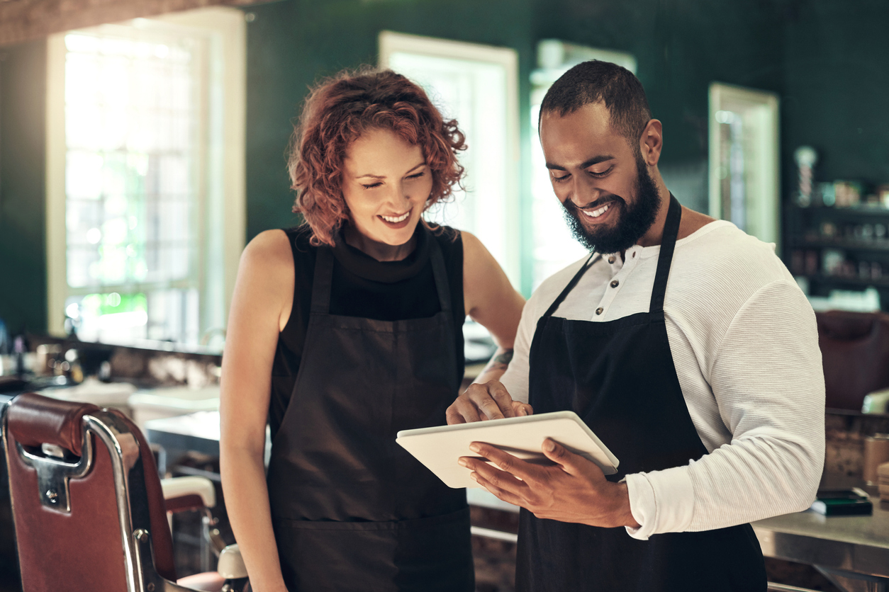 Two salon staff members using a tablet for training, emphasizing the importance of training staff and promoting a new salon program.