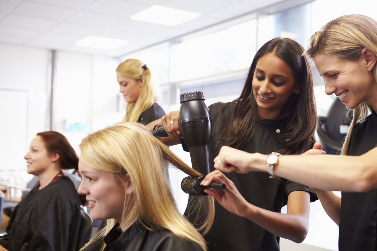 Hair salon staff working with clients, demonstrating the efficient workflow and customer satisfaction achievable with salon scheduling software.<br />
