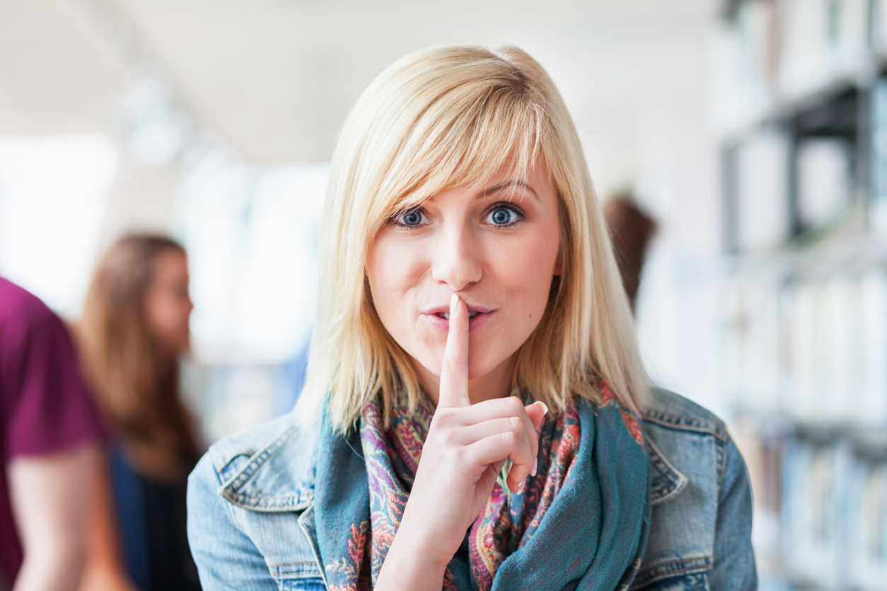 A smiling salon owner with a finger to her lips, symbolizing the secrets of successful hair salon ownership.